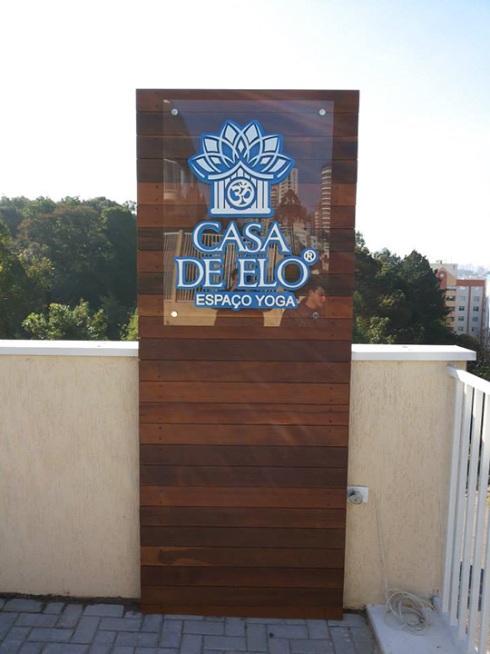Visão frontal da Placa em acrílico com a logo em painel de madeira